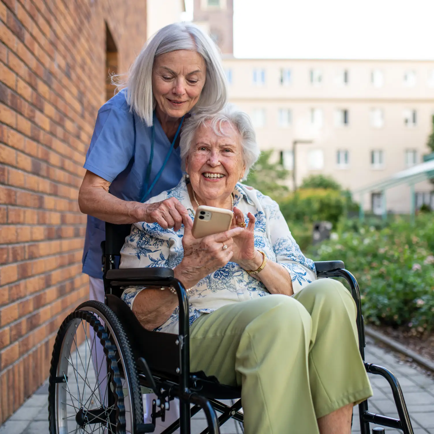 New York Care professional assisting an older adult using a smartphone, representing supportive care coordination and daily living assistance